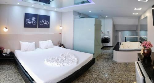 巴西利亚科罗拉多汽车旅馆（仅限成人）的一间带白色大床的卧室和一间浴室
