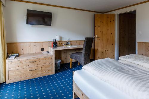 Bühler兰格福斯恩酒店的一间卧室配有一张床、一张桌子和一个水槽