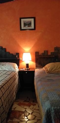 康塞普西翁德阿塔科Portal de los Farolitos的一间卧室设有两张床和一张桌子上的台灯。