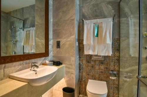 桑给巴尔Golden Tulip Zanzibar Airport Hotel & Spa的一间带水槽、卫生间和淋浴的浴室