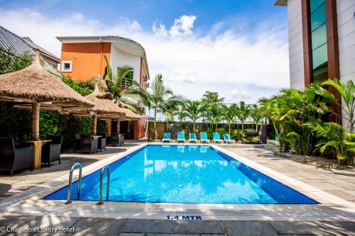 哈科特港Charleson Luxury Hotel的度假村的游泳池,配有椅子和遮阳伞