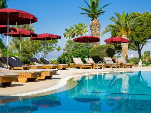 利马索尔圣拉弗尔度假村的一个带遮阳伞和椅子的游泳池以及棕榈树