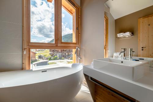 蒙热内夫尔Le Chalet Blanc Hôtel & Spa的一间带大浴缸、水槽和窗户的浴室