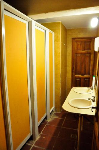普尔马马尔卡Giramundo Hostel Purmamarca的一间带两个盥洗盆的浴室和一个带黄色墙壁的卫生间