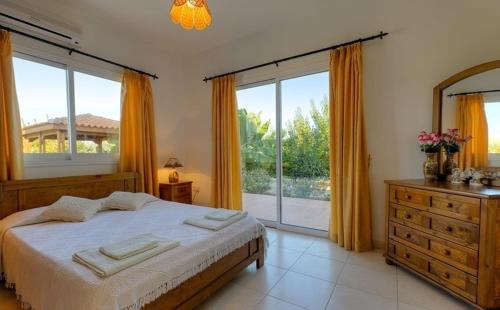 佩亚Peyia Villas Cyprus的一间卧室设有一张床和一个大窗户