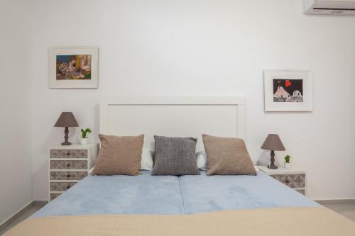 海若克利欧Eleni's Studio的白色卧室配有蓝色的床和两盏灯