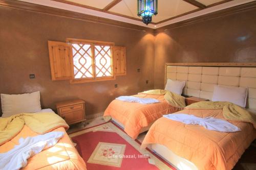 伊姆利尔Gite Ghazal - Atlas Mountains Hotel的一间卧室设有三张床和窗户。