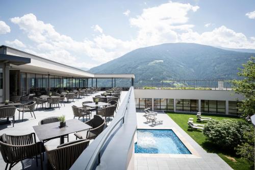 纳兹-夏韦斯Das Mühlwald - Quality Time Family Resort的一个带桌椅的阳台和一个游泳池