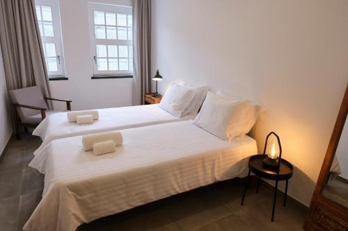 英雄港Casas do Mercado - Casa Sirius的一间卧室配有两张带白色床单和灯的床