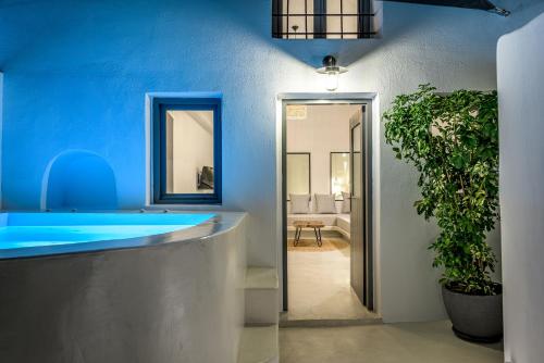 费拉Anila Suites的浴室设有蓝色浴缸和盆栽植物