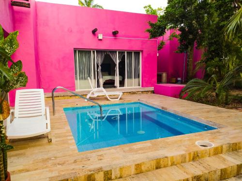 科苏梅尔Casa Isabella的粉红色的房子,前面设有一个游泳池