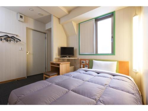 神户R&B Hotel Kobe Motomachi - Vacation STAY 15385v的一间卧室设有两张床、一张桌子和一个窗口。