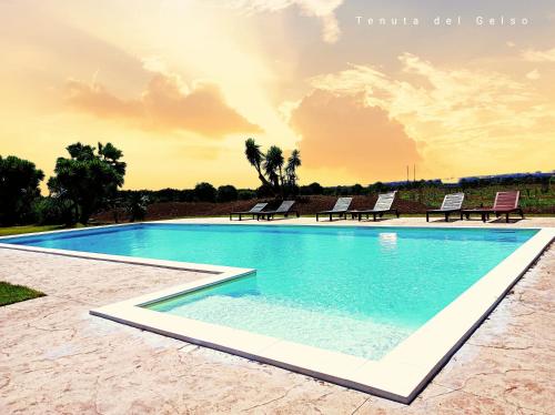 卡塔尼亚Tenuta del Gelso的一个带椅子的游泳池,享有日落美景