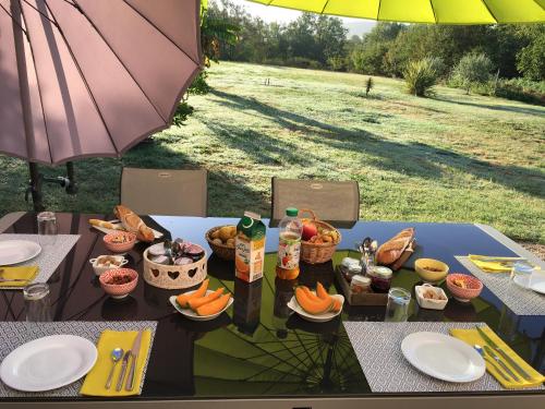 Saint-Sylvestre-sur-LotLocation Chambres d'Hôtes Clodeguy No 2的一张带食物的野餐桌和一把雨伞