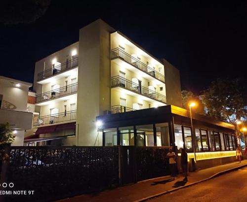 里乔内Hotel Garisenda B&B - in Centro a Riccione -的一座晚上有人站在建筑前面的建筑
