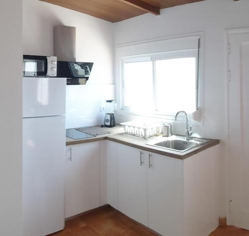 弗龙特拉Loft Con Encanto的厨房配有白色橱柜、水槽和窗户。