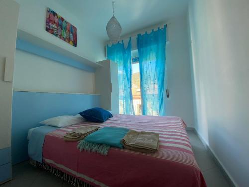 蒙特罗索阿尔马雷Raggi di Sole的一间卧室配有一张带蓝色窗帘的床和一扇窗户