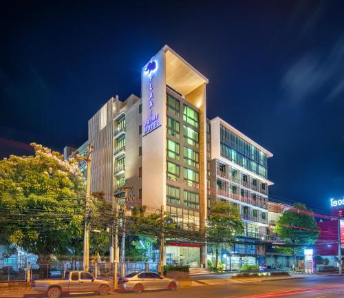 罗勇PLAAI Prime Hotel Rayong SHA Extra Plus的一座高大的建筑,前面有汽车停放