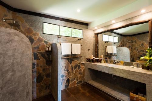 涛岛龟岛高地泳池别墅酒店的石质浴室设有水槽和镜子