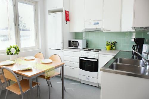 约恩苏ISLO Hostel的厨房配有白色橱柜、桌子和水槽。