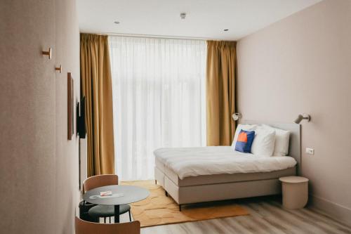 海牙Hotel Bries Den Haag - Scheveningen的酒店客房配有一张床铺和一张桌子。