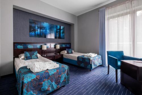 Cedzyna乌洛捷斯科酒店的酒店客房设有两张床、一张桌子和一张书桌。