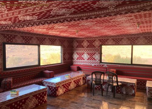 瓦迪拉姆Desert Mars Camp & Tours的红色的墙壁和带桌椅的窗户。