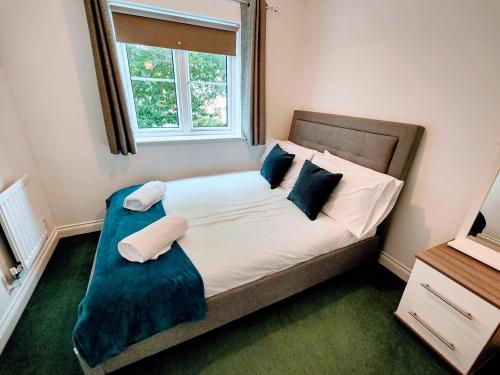 伊斯特雷格CEDAR HOUSE - Spacious 4Bedroom House 2Bath Kitchen SmartTV Lounge Garden Wifi FreeParking的一间卧室配有带两个枕头的床和窗户