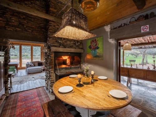 奥茨胡恩De Cango Farm的一间带桌子和壁炉的用餐室