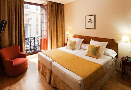 塞维利亚Sercotel Las Casas de los Mercaderes的酒店的客房 - 带一张床、椅子和窗户