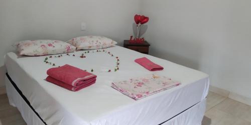 卡皮托利乌Suite independente em casa de fazenda的一张白色的床,上面有粉红色的床单和枕头