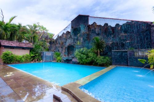 外南梦Hotel Mahkota Plengkung by ecommerceloka的一座带岩石墙的建筑前的游泳池