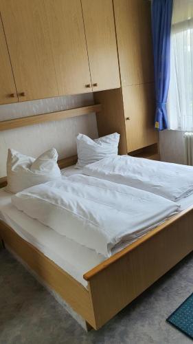 瓦尔德克Pension Backhaus的一张配有白色床单和枕头的大床