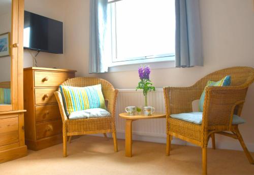 圣安德鲁斯No12 Bed and Breakfast, St Andrews的一间设有两把椅子、一张桌子和一个窗户的房间