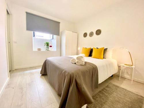 纳扎雷BrightHouse - Modern Apartments in Sítio Nazaré的白色卧室配有一张带黄色枕头的大床