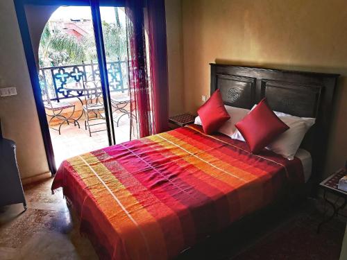 马拉喀什La Perle de l'Atlas by Golf Resort的一间卧室配有一张带红色枕头的床和一个阳台