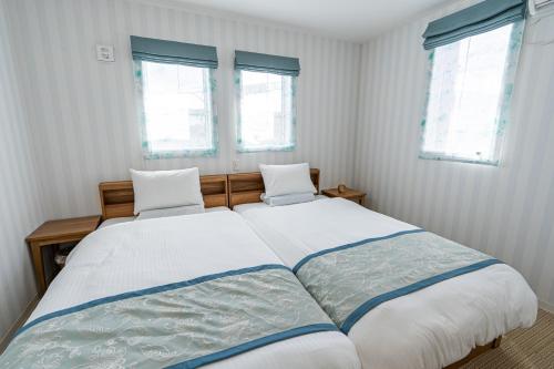 宫古岛Ecot Irabu Bridge Sunset Hills的一间卧室设有一张大床和两个窗户
