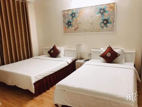 下龙湾Dragon hotel的配有白色床单的客房内的两张床