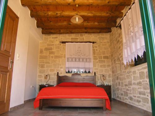 KaloniktisStratos Villas的一间卧室设有红色的床和石墙