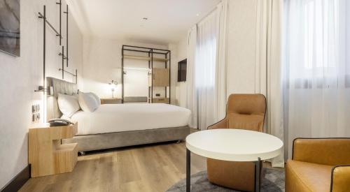 毕尔巴鄂Hotel Ilunion San Mamés的卧室配有1张床、1张桌子和1把椅子