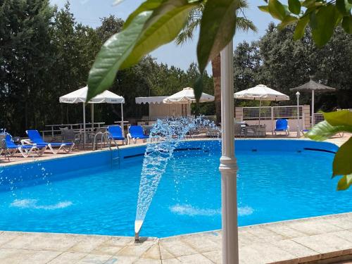 Navalvillar de Pela唐璜酒店的游泳池中的喷泉,配有椅子和遮阳伞