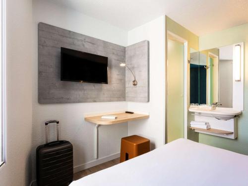 波尔多波尔多中心宜必思快捷酒店 - 圣让火车站的一间卧室配有一张床和一张桌子,墙上配有电视