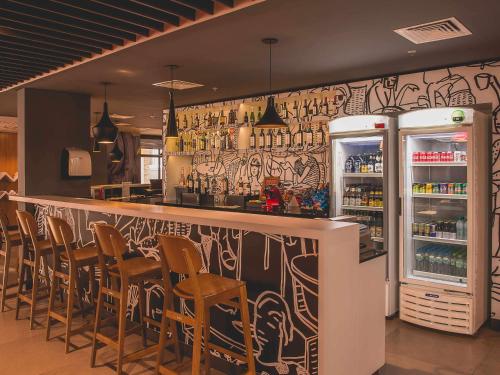卡洛斯-巴尔博萨ibis Carlos Barbosa的餐厅设有酒吧、椅子和冰箱