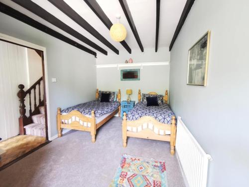 LlanfyrnachWellstone Cottages - Jasmine的白色墙壁客房的两张床
