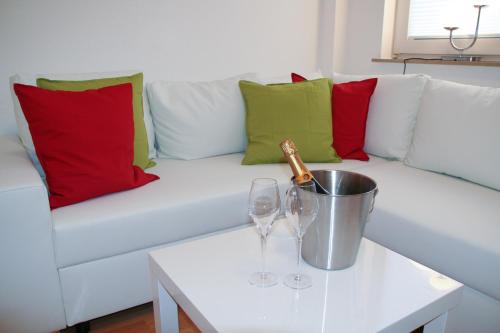 维岑豪森Premium Ferienwohnung Sonnenaufgang的白色沙发、红色和绿色枕头以及一瓶香槟