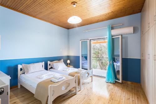 EvropoúloiOlive Tree House的配有两张床铺的蓝色墙壁和窗户
