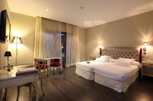 ChuecaHotel Spa Villa Nazules的酒店客房配有两张床和一张书桌