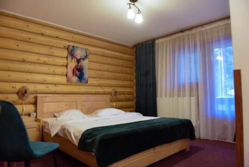 欧巴西亚洛德洛伊Pensiunea Vanatorul的一间卧室设有一张床和木墙