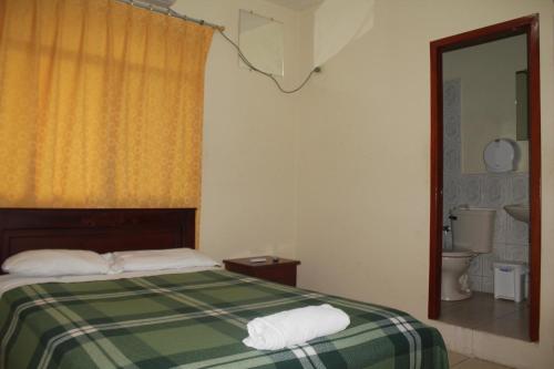 曼塔三月玫瑰旅舍的一间带绿色和白色床的卧室以及一间浴室。