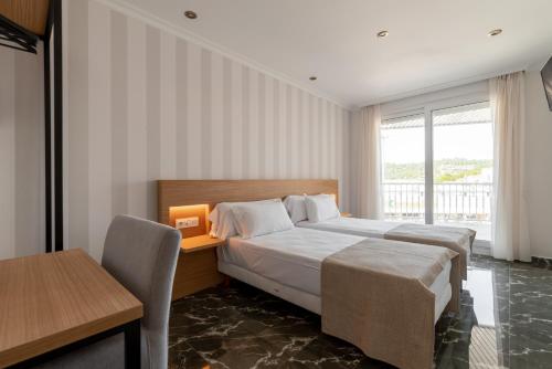 奥伦塞Hotel Condado Ourense的一间卧室配有一张床、一张书桌和一个窗户。